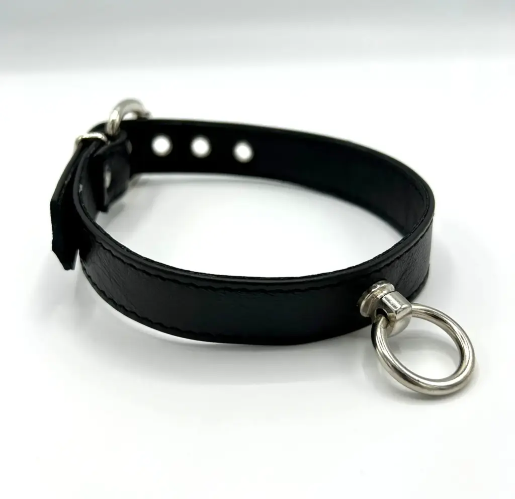 Schwarzes Halsband mit Ring der O auf weißem Hintergrund seitlich